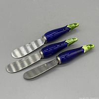 Three eggplant-handle spreaders front view