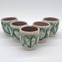 Front group view of five cream and green hand-painted earthenware cups