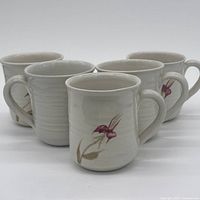 Front angled view of all five mugs showing floral design and handles