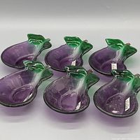 Six purple and green eggplant-shaped glass bowls displayed together