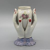 front view of ceramic hands vase with floral decal and iridescent finish