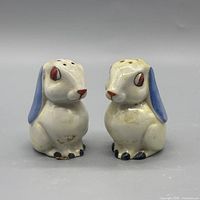 Front view of both ceramic rabbit shakers showing glaze, color details and wear