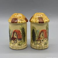 Front view of both shakers showing cottage motif and straw roofs