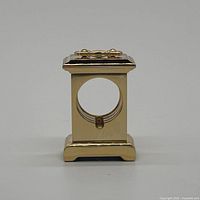 Front view of brass clock case showing circular opening and top finial