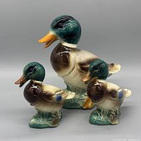 Front view of all three glazed porcelain duck figurines