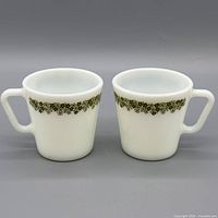 Front view of both milk glass mugs showing full pattern and shape
