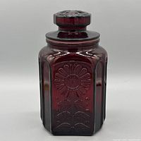 Front view of ruby red Wheaton canister showing sunflower motif and lid