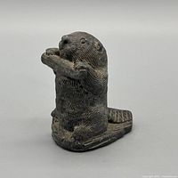 Front angled view of ceramic beaver holding log