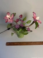 Front view of lamp showing ceramic base, glass flowers, leaves, power cord and ruler for scale