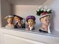 Four head vases side by side on shelf