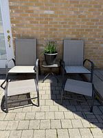Front view of two sling chairs, two ottomans, and side table