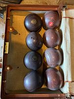 Open suitcase containing eight lawn bowling balls
