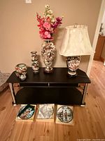 Overall view of four Satsuma ceramics on black stand with three boxed plates below