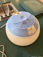 Round white and blue electric towel warmer with power cord visible on countertop
