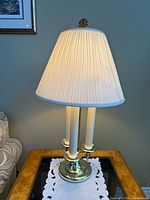 Full view of one brass bouillotte lamp with shade