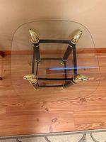 Top view of square glass side table showing brass finials and leg framework