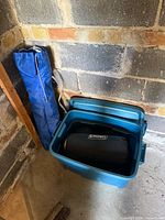 Blue tote with lid next to blue chair bag