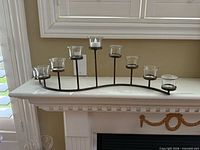 Tabletop metal candelabra with eight glass tealight cups on mantel