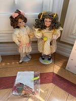 Both dolls on stands with certificate in plastic sleeve