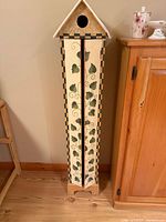 Front view of closed birdhouse cabinet showing painted vine design and checkerboard trim