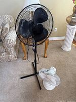 Black pedestal fan and white desk fan full view