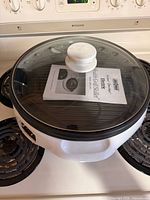 grill-skillet with glass lid and manual on stovetop