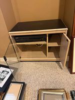 Cabinet open showing interior shelf and electronics compartment