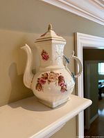 Front view of white porcelain lidded floral pitcher