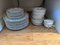 Full group showing stacks of plates, bowls and two teacups stored in cupboard