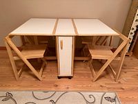 Folding table expanded with two chairs stored underneath