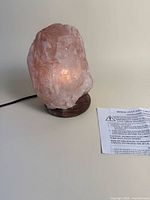 Front view illuminated Himalayan salt lamp on wood base with cord visible