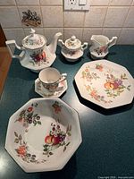 Group of teapot, creamer, covered sugar, cup & saucer, large bowl, octagonal plate and pitcher on countertop