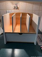 Front view showing three vertical slots and slatted drawer