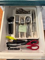 Drawer view showing complete flatware set in organizer plus additional utensils beneath
