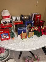 Overall view of assorted boxed village pieces, loose accessories and centerpiece on lace table