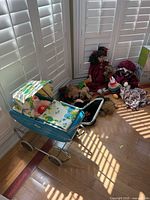 Overall view showing blue doll stroller and pile of dolls and plush toys