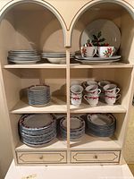 Full cabinet view showing plates, cups, saucers and bowl in both holiday patterns