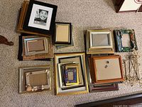 Three stacked groups of assorted picture frames on carpet