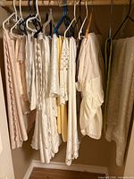Closet rod showing group of hanging white and cream tablecloths
