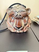 Front view of carved lion head purse showing facial detail and strap