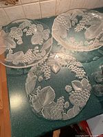 Three clear glass platters with raised grape and leaf pattern