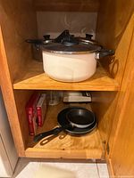 Fondue pot on upper shelf, two non-stick frying pans below