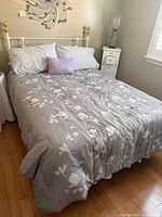 Fully assembled white metal bed with bedding, shows overall condition and size
