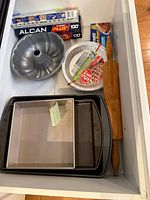 Drawer view showing bundt pan, pie plates, foil boxes, rolling pin, and stacked baking pans