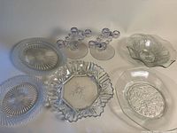 Group shot showing all seven clear pressed-glass pieces