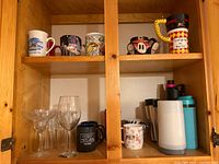 Cabinet shelves showing full assortment of mugs, glasses and travel drinkware