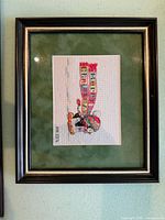 Framed penguin cross-stitch with green mat and wood-tone frame