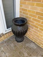 Full view of urn planter next to wall shows overall shape and finish