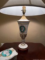 Lamp showing porcelain body with cameo medallion and wood base; dish visible