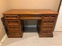 Front view of solid wood pedestal desk showing seven drawers and hardware